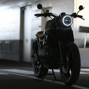 A sleek cafe racer motorcycle parked indoors with strong lighting contrast.